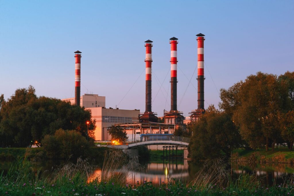 View of an industrial plant with tall chimneys by a lake in Minsk, Belarus during the day.